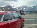 Alps, Austria Ã¢â¬â July 27, 2017:: Family resting in Alps Austria. Red car for traveling is standing near.